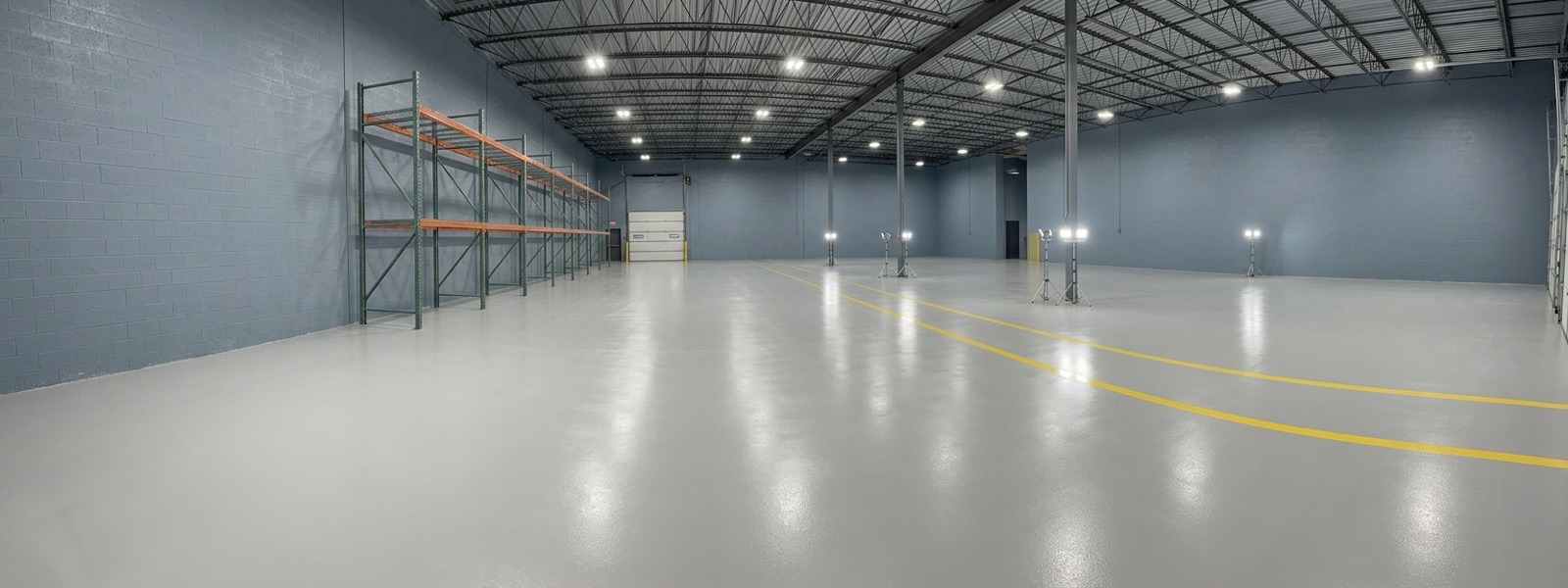 Wide view of a finished light gray commercial epoxy floor in a warehouse bay