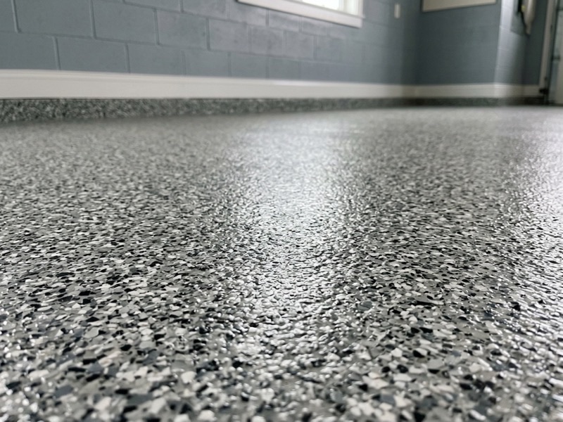 Close-up of a gray, black and white decorative flake epoxy floor with a satin topcoat